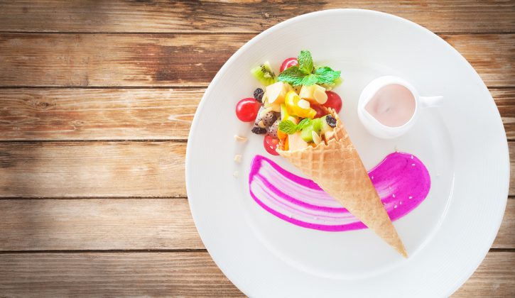 Fruit salad in an ice cream cone on wood background