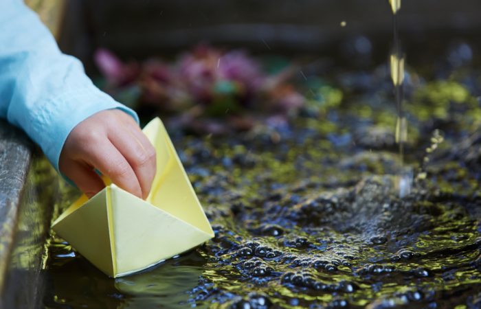 Boy Playing with Paper Boat in Water