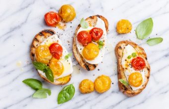 Crostini with roasted tomatoes and buffalo mozzarella and basil leaves