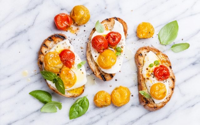 Crostini with roasted tomatoes and buffalo mozzarella and basil leaves