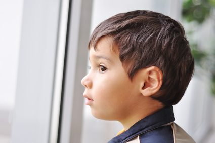Portrait of little pretty thoughtful boy looking out of the window