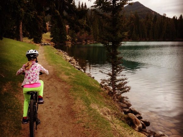 Girl-riding-bike-along-lake