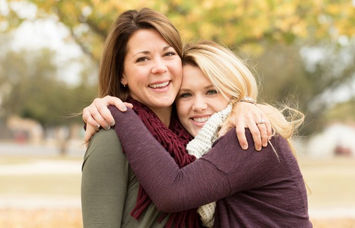 Mother and teenage daughter hugging.