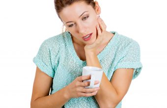Sleepy woman holding a cup of coffee, falling asleep