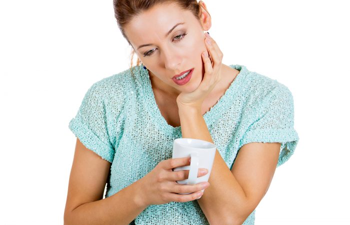 Sleepy woman holding a cup of coffee, falling asleep