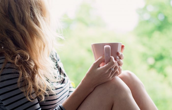 Peaceful woman relaxing at home with cup of tea or coffee