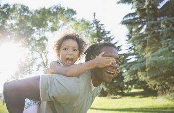 Portrait of playful girl covering fathers eyes in park