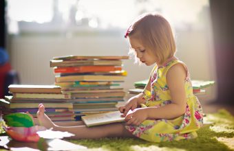 Child reading stack of books