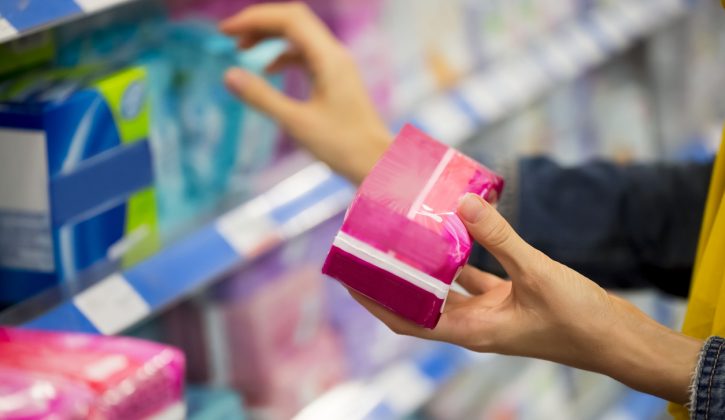 Unrecognizable woman is choosing between pad and tampon in the store, selective focus